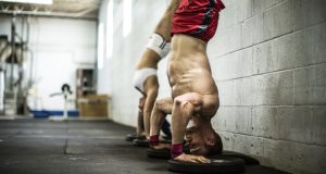 man and woman doing handstand pushups